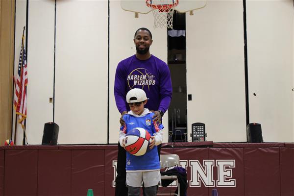  Harlem Wizard player standing behind a Duzine Elementary student