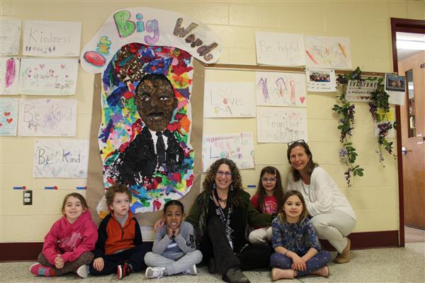  students and their teachers posing in front of their mural