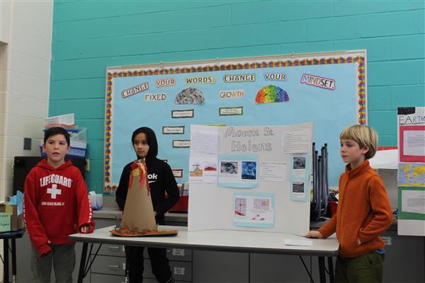 3 students stand in front of their volcano project 