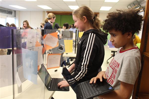  2 students using tablets look at a project 