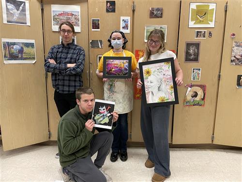 4 students showing off their winning art work 
