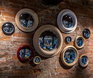 11 round mirrors hang on brick wall 