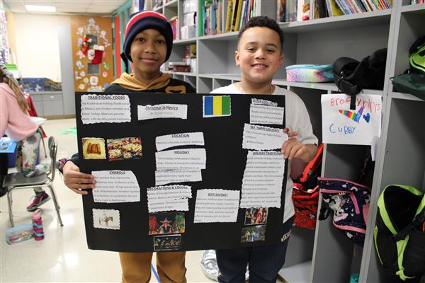   two students holding their holidays around the world presentation
