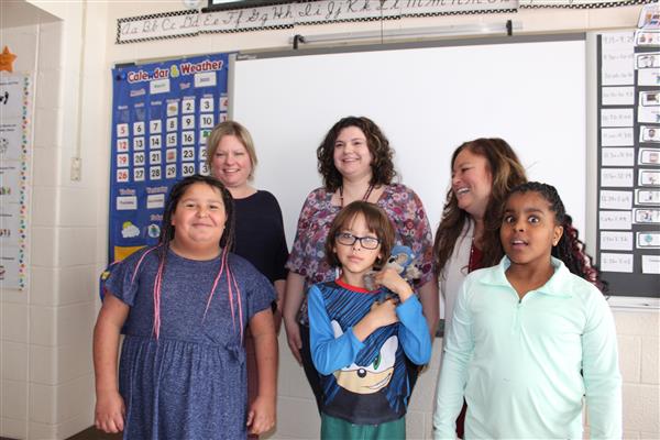  students and teachers in front of white board 