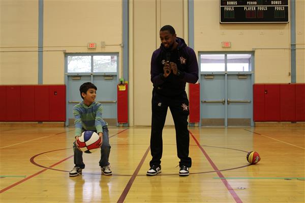  Harlem Wizards player demonstrating skills for Lenape student