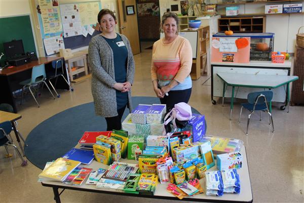 2 women standing in front of table of supplies 