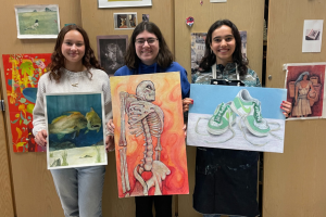  three students holding artwork