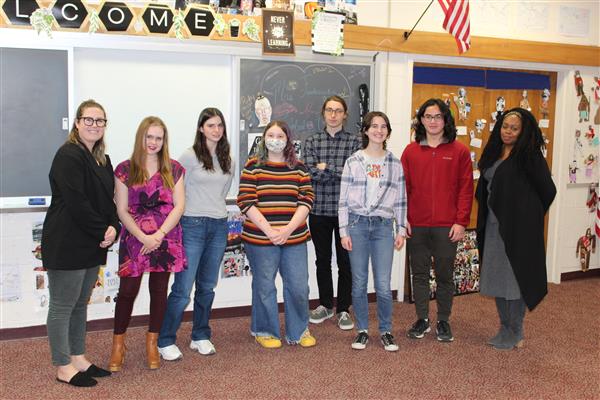  students, principal and teacher stand in front of white board 