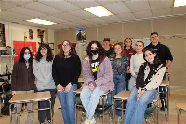  students smiling sitting on desks 