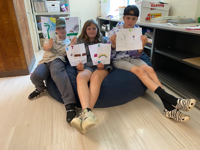 students on beanbag showing off book 